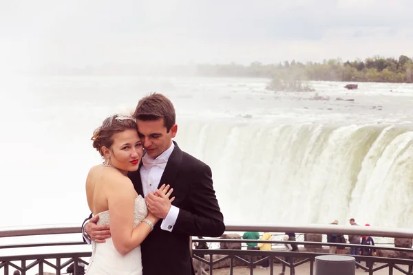 Novia y novio abrazando cerca de la cascada — Foto de Stock