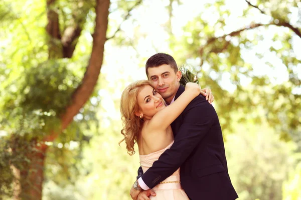 Beautiful bride and groom embracing in the park — Stock Photo, Image