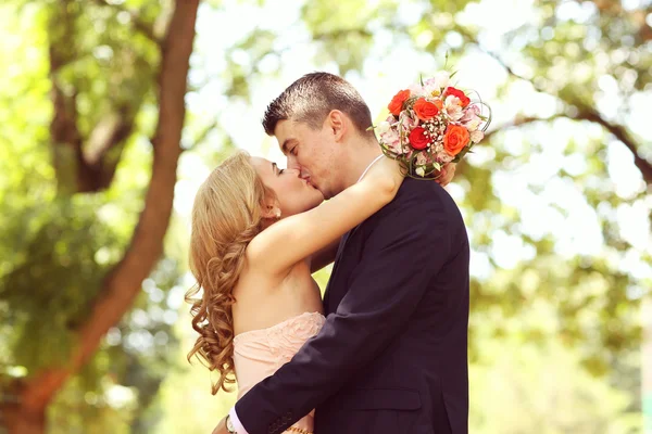 Vackra bruden och brudgummen embracing i parken — Stockfoto
