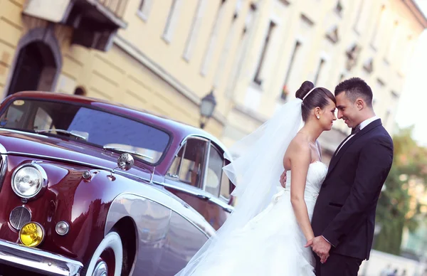 Hermosa novia y novio abrazando cerca de coche clásico — Foto de Stock