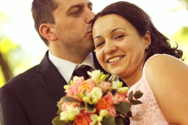 Joyful bridal couple embracing in the park — Stock Photo, Image