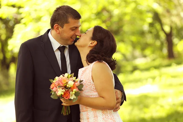 Joyful bridal couple embracing in the park — Stock Photo, Image