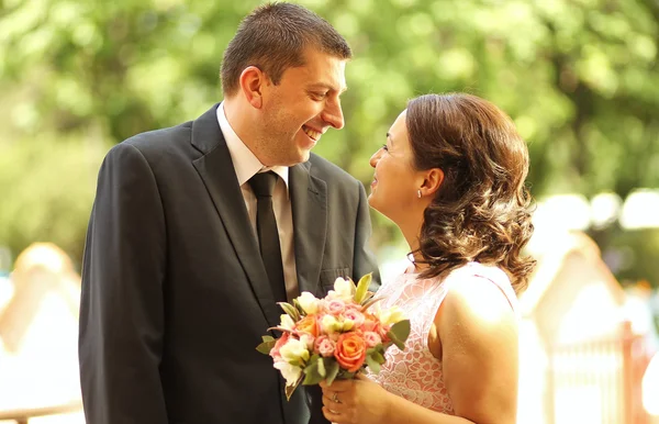 Joyful bridal couple embracing in the park — Stock Photo, Image