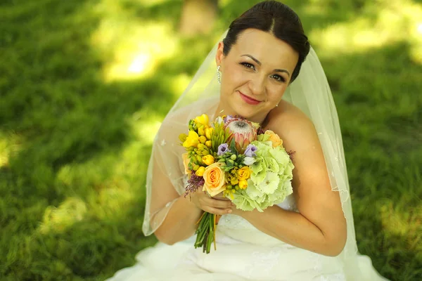 Örömteli menyasszony kezében gyönyörű csokor, a parkban — Stock Fotó