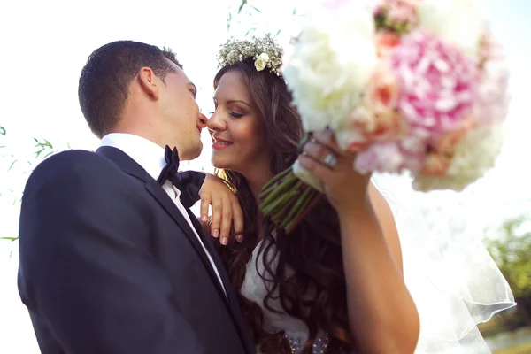 Schöne Braut und Bräutigam mit Blumenstrauß am Hochzeitstag — Stockfoto