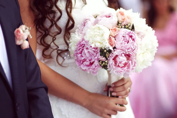 Schöne Braut und Bräutigam mit Blumenstrauß am Hochzeitstag — Stockfoto