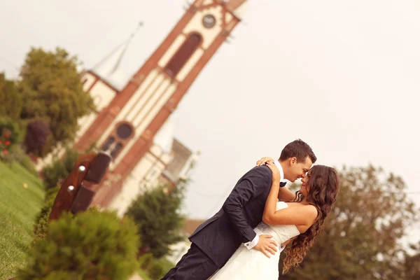 Güzel gelin ve damat yanında kilise kucaklayan — Stok fotoğraf