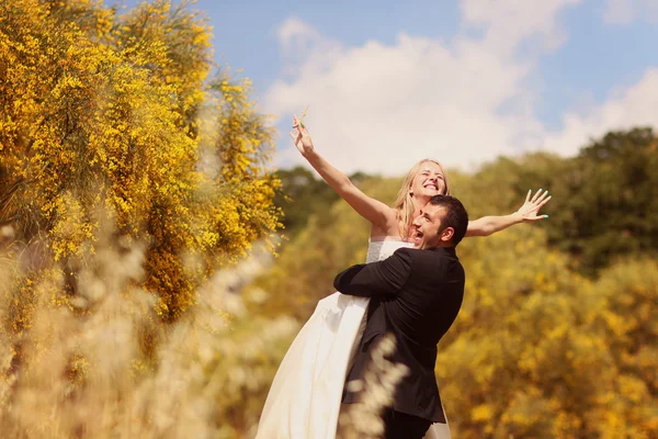 Joyful bride and groom having fun in nature — Stock Photo, Image