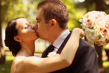 Güzel gelin ve damat kucaklayan ve parkta öpüşme