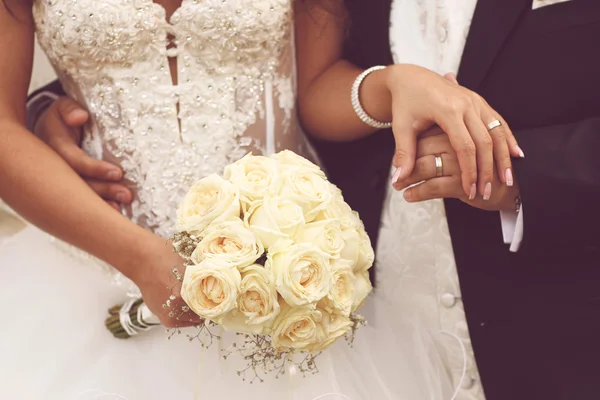 Schöne Braut und Bräutigam mit Blumenstrauß am Hochzeitstag Händchen haltend — Stockfoto