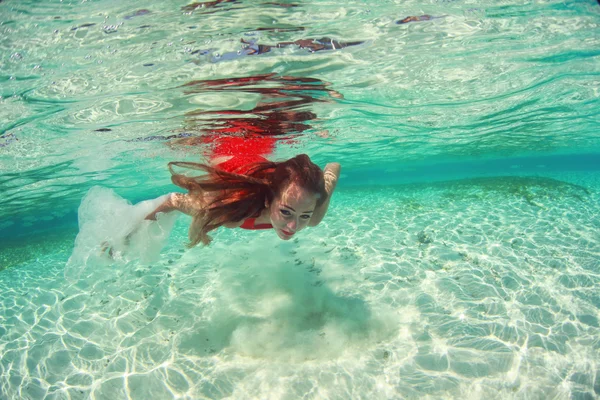 Beautiful young women in red dress diving in the ocean near Maldives islands — Stock Photo, Image