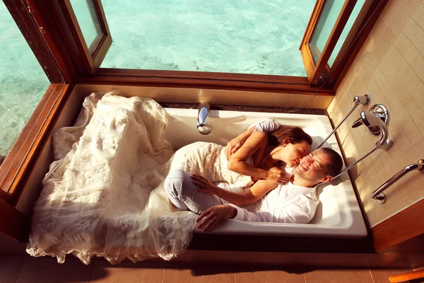 Braut und Bräutigam legen sich in einer Badewanne in einer Wasservilla auf den Malediven nieder — Stockfoto