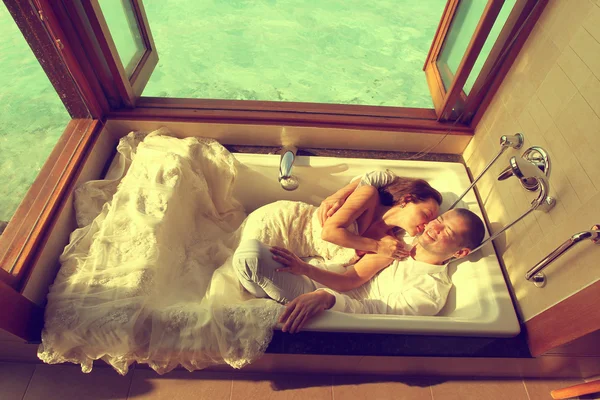 Mariée et marié allongés dans une baignoire dans une villa d'eau près des Maldives — Photo