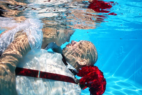 Hermosa novia y novio besándose y abrazándose bajo el agua en la piscina — Foto de Stock