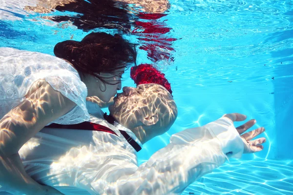 Hermosa novia y novio besándose y abrazándose bajo el agua en la piscina — Foto de Stock