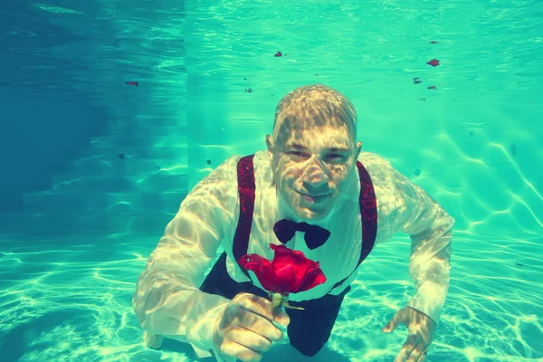 Элегантный жених ныряющий под водой в бассейне — стоковое фото
