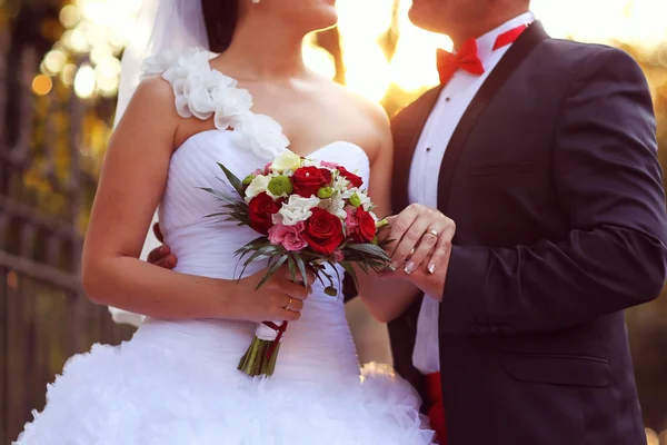 Bela noiva e noivo abraçando e segurando buquê de flores — Fotografia de Stock