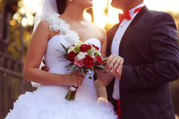 Bella sposa e lo sposo abbracciando e tenendo bouquet di fiori — Foto Stock