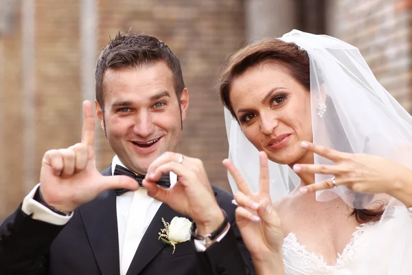 Porträt von Braut und Bräutigam, die mit Händen Liebeszeichen machen — Stockfoto