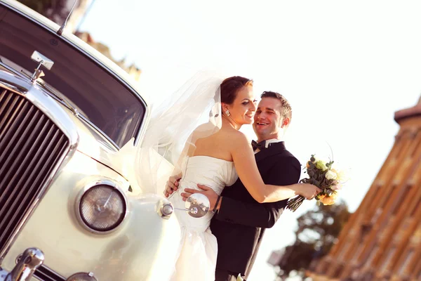 Belle mariée et marié embrassant près de voiture classique en ville — Photo