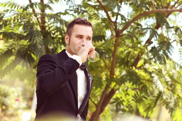 Elegant groom on wedding day having a glass of champagne — Stock Photo, Image