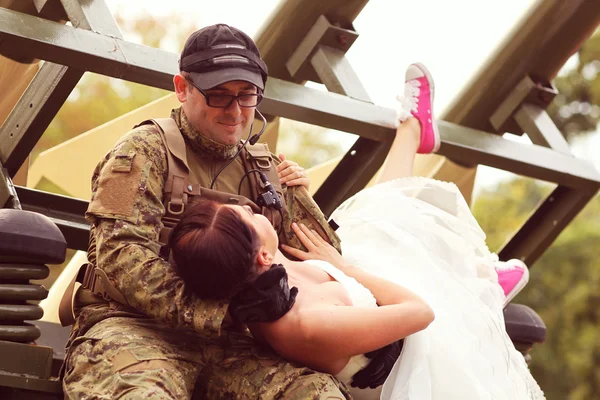Bruden embracing med brudgummen i armén kostym — Stockfoto