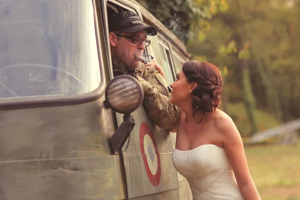 Bruden embracing med brudgummen i armén kostym — Stockfoto