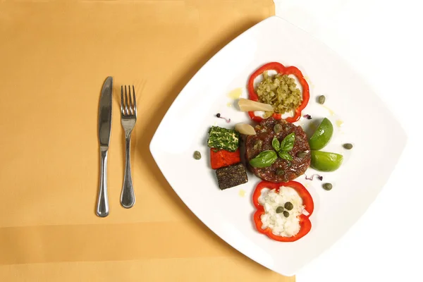 Delicious gourmet food at restaurant on plate with fork and knife — Stock Photo, Image