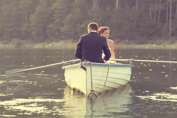 Beautiful bride and groom in a boat on the lake — Stock Photo, Image