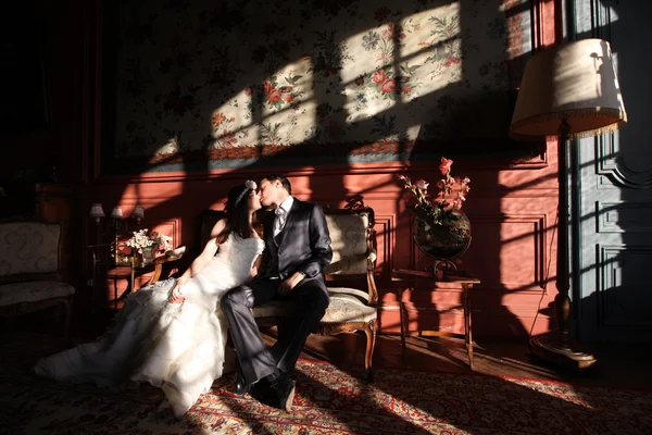Красивая невеста и жених обнимаются и целуются в старинной комнате — стоковое фото