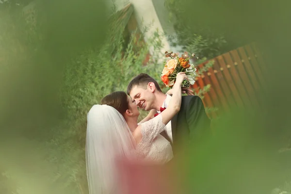 Vackra bruden och brudgummen embracing och hålla brudbukett — Stockfoto