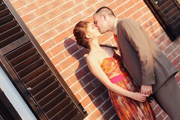 Beautiful bride and groom embracing near brick building — Stock Photo, Image