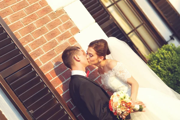 Hermosa novia y novio abrazando cerca del edificio de ladrillo — Foto de Stock