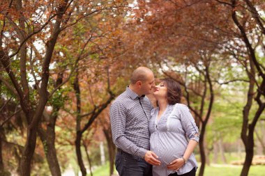 Mutlu ve genç hamile çift doğada kucaklayan