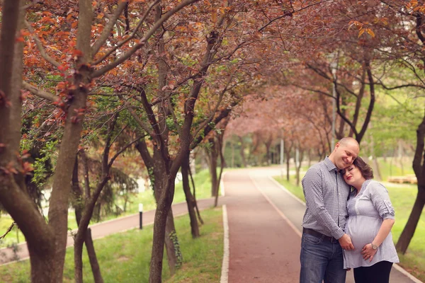 Happy and young pregnant couple embracing in nature — Stock Photo, Image