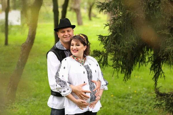 Happy and young pregnant couple embracing in nature — Stock Photo, Image