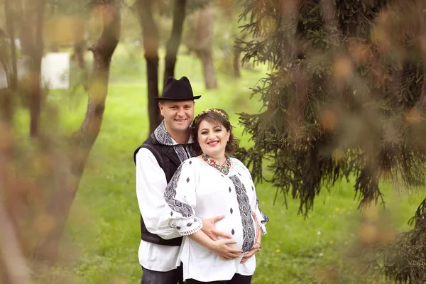 Happy and young pregnant couple embracing in nature — Stock Photo, Image