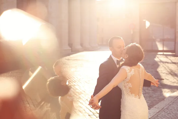 Beautiful bridal couple embracing and kissing near columns — Stock Photo, Image