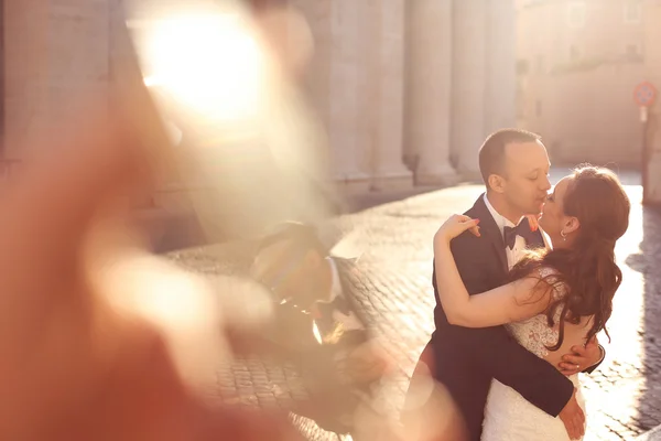 Piękne suknie ślubne para obejmując i całując w pobliżu kolumny — Zdjęcie stockowe