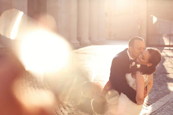 Vackra brudparet omfamnar och kysser nära kolumner — Stockfoto