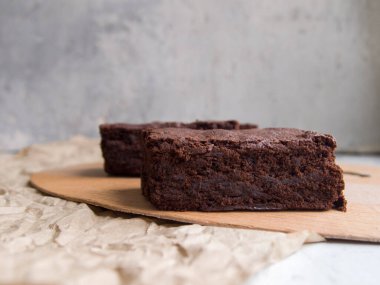 Ev yapımı iştah açıcı browniler. Tarafsız gri bir arka planda, tahta bir tahtanın üzerinde lezzetli siyah çikolatalı pasta dilimleri. Süssüz basit bir tatlı..