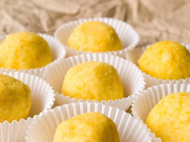 Buruşuk kağıt üzerinde beyaz şeker paketleriyle yuvarlak sarı şekerler üzerine yumuşak bir odak.