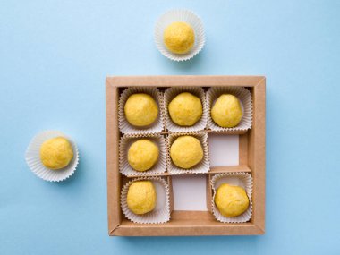 Turuncu aromalı parlak sarı yuvarlak şekerli bir şeker kutusunun üst görüntüsü. Diğerlerinden ayrı olarak kutunun dışında iki tane şeker var..