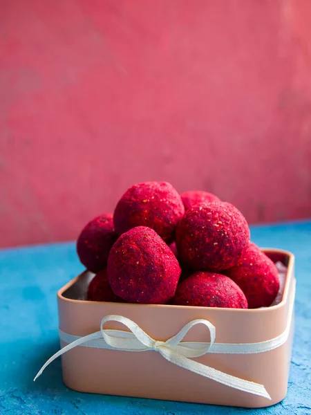 Pembe ve mavi arka planda kırmızı çikolatalı mantarlı Sandy kahverengi şeker kutusu. Süblimleşmiş ahududularla kaplı tatlılar..