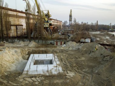 İnşaat alanının en üst görüntüsü. Beton ve çelikten bir temel inşa etme süreci. Köprü desteğinin iskeleye yakın bir yerde inşaatı. Endüstriyel şehir manzarası.