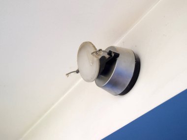 Örümcek ağı ve tozla kaplı bir duvar lambası. Tavanın altındaki duvarda alışılmadık bir ışık var. Oda uzun zamandır temizlenmemiş..