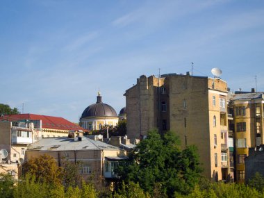 Sıcak ve güneşli bir günde şehir manzarası. Eski tuğla evler ve kahverengi kubbeli bir bina. Ağaçlardaki yapraklar sararmaya başladı..