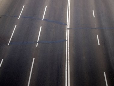 Hiç kimsenin olmadığı yol manzarası var. Yüzeyde tamir sonrası yamalar var. Koyu gri soyut nötr arkaplan.