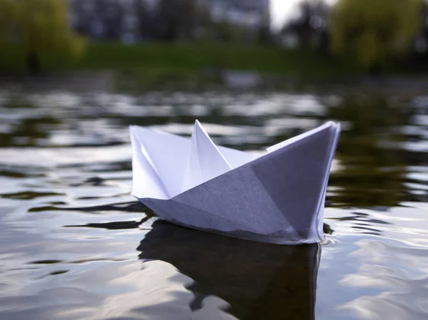Mavi suda beyaz kağıt tekne. Origami gemisi nehirde seyrediyor. Umut ve geleceğin sembolü.