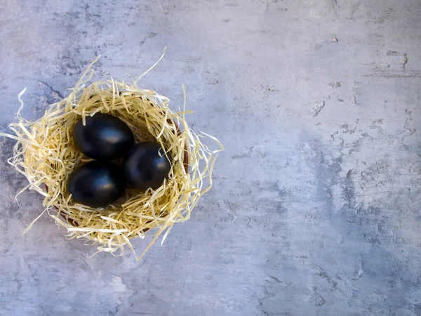 Vista Superior Tres Huevos Negros Nido Paja Sobre Fondo Hormigón — Foto de Stock